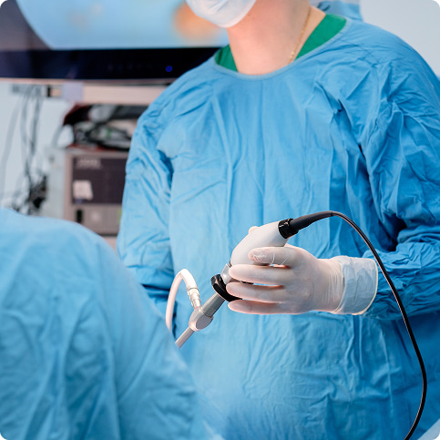 Operatore sanitario in guanti e camice sterile tiene un dispositivo medico in sala operatoria.