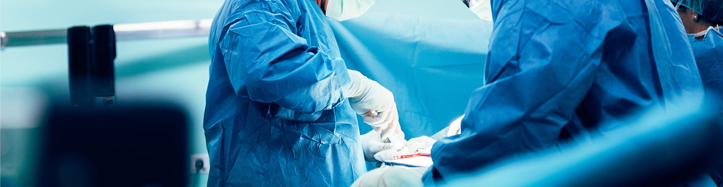 Operazione chirurgica in corso: tecnici in guanti e camici chirurgici coordinano precisione in sala operatoria.