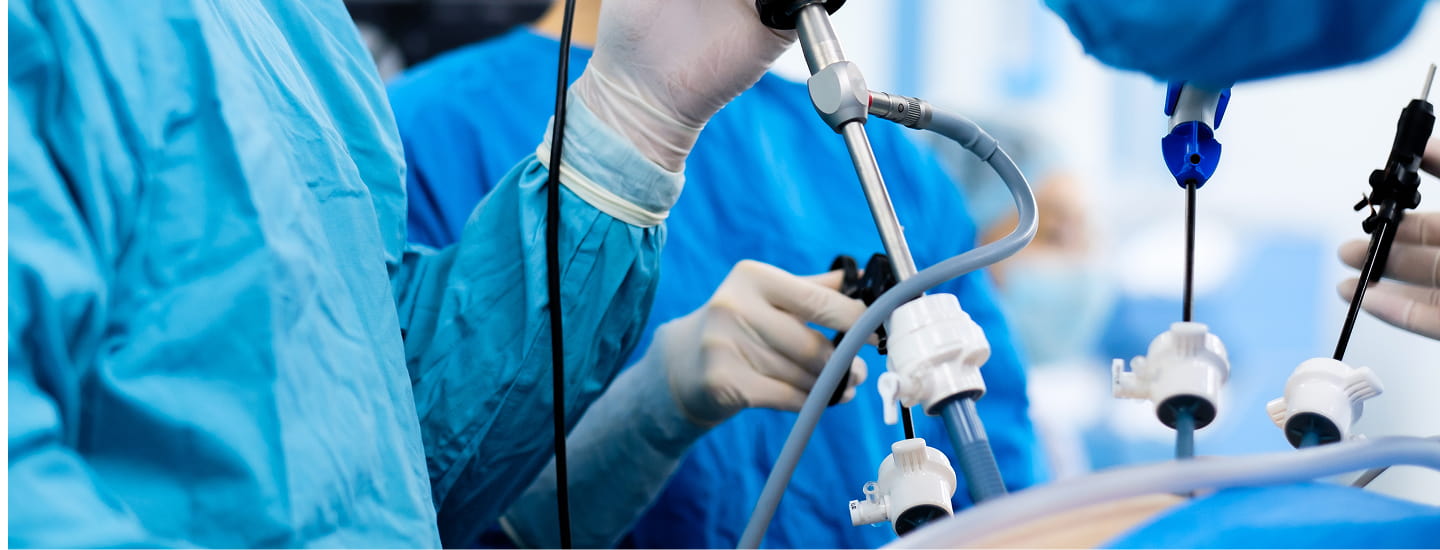 Caso chirurgico in salaoperatoria: mani guantate manovrano strumenti medici, con attrezzatura e supporti tubulari in primo piano.
