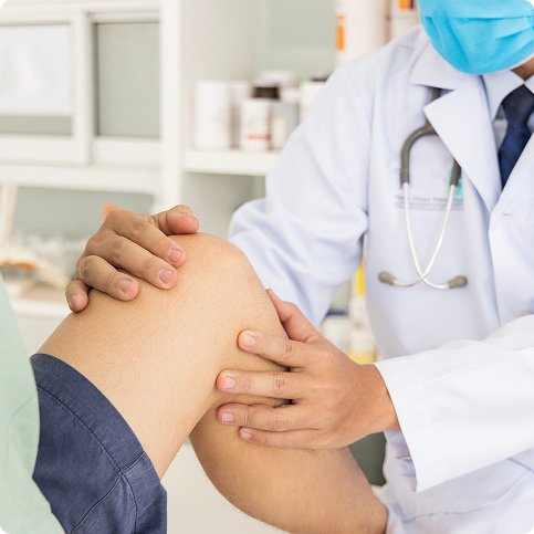 Medico che esegue un esame di controllo su un ginocchio del paziente in studio medico, mani gentili e stetoscopio sullo sfondo.