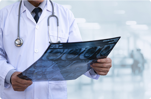 Medico in camice bianco esamina una radiografia, sfondo clinica neutro, focus sulla diagnostica radiologica.