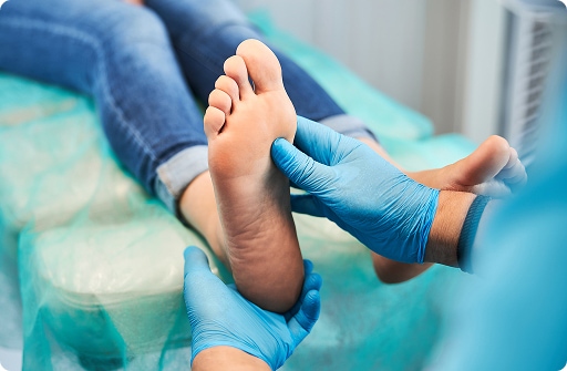 Professionali infermieri o medici esaminano e controllano il piede di un paziente disteso su un lettino, indossando guanti blu.