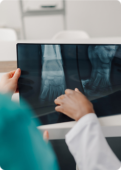 Infermiera esamina una radiografia del piede e del dito, mostrando una visita medica in laboratorio con immagini diagnostiche.