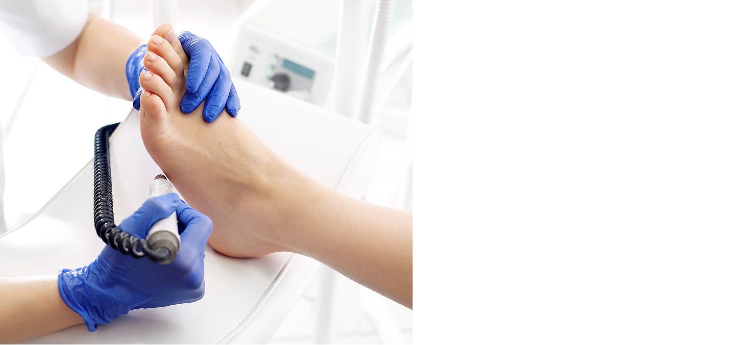 Procedura medica: un professionista esamina un piede sostenuto da una mano, con guanti blu, in ambiente clinico.